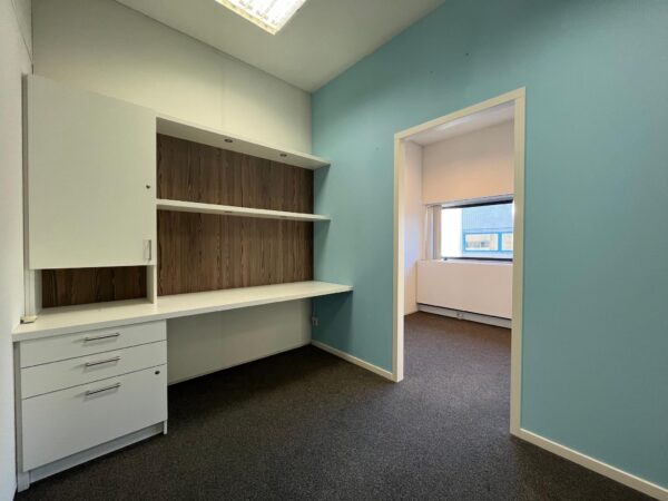 Kleine kantoorruimte in Leidse Rijn met ingebouwd bureau, wandkast en blauwe muren.
